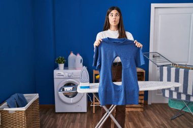 Çamaşır odasında ütü yapan genç esmer kadın, yanık demir gömlekli, ağzı açık, şaşı gözlü, çılgın ve komik bakışlı.. 