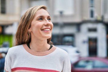 Young blonde woman smiling confident looking to the side at street