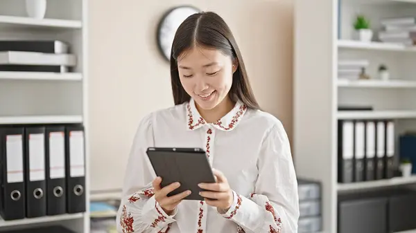 Young chinese woman business worker using touchpad smiling at office