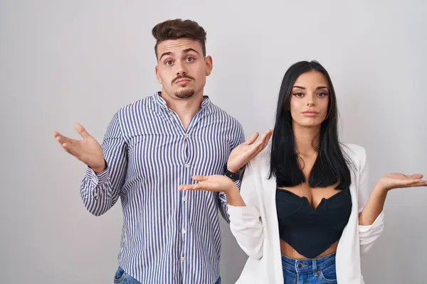 Young Hispanic Couple Standing White Background Clueless Confused Expression Arms — Stock Photo, Image