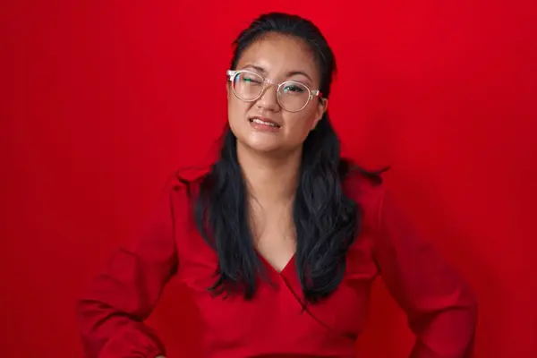 Asiatisk Ung Kvinna Står Över Röd Bakgrund Blinkar Tittar Kameran — Stockfoto