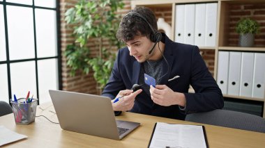 Ofisteki kredi kartıyla yapılan bir telefon görüşmesinde kulaklık takan İspanyol bir iş adamı.