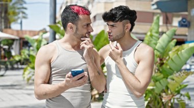 Parkta akıllı telefon kullanan iki erkek.