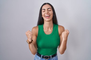 Young woman standing over isolated background very happy and excited doing winner gesture with arms raised, smiling and screaming for success. celebration concept. 