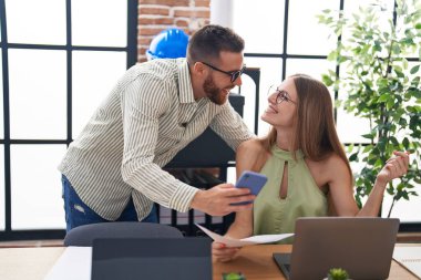 Man and woman business workers using laptop and smartphone at office