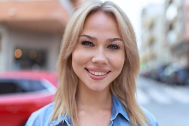 Sokakta kendine güvenen genç sarışın kadın gülümsüyor