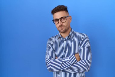 Gözlüklü, kuşkucu ve gergin sakallı İspanyol bir adam. Yüzünde çapraz kollu tasvip etmeyen bir ifade. negatif kişi. 