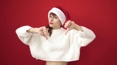 Kafkasyalı genç bir kadın, kırmızı arka planda noel şapkası takıyor.