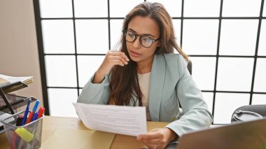 Genç, zarif ve güzel bir İspanyol kadının portresi ofis masasında otururken iş belgelerini okumaya odaklanmış, bilgisayarının içinde çalışıyor..