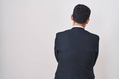 Yakışıklı İspanyol bir adam beyaz arka planda dikiliyor arkasını dönüp kollarını kavuşturuyor. 