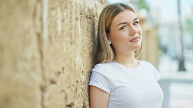 Sokakta kendine güvenen genç sarışın kadın gülümsüyor