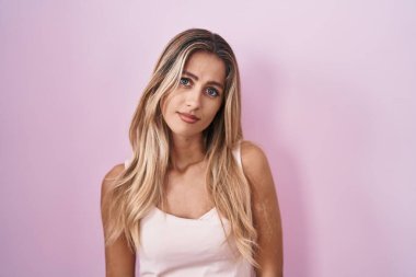 Pembe arka planda duran genç sarışın kadın uykulu ve yorgun görünüyor, yorgunluktan yorgun ve akşamdan kalma, sabahları tembel gözler.. 
