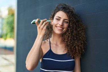 Genç ve güzel İspanyol kadın gülümsüyor. Caddedeki akıllı telefondan kendine güvenen bir sesli mesaj dinliyor.