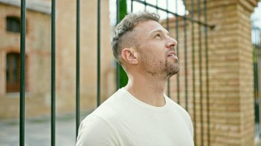 Sokakta ciddi bir yüzle gökyüzüne bakan genç adam