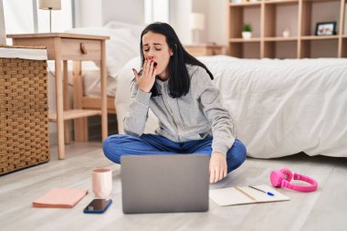 Beyaz kız öğrenci, yerde ders çalışıyor. Yatak odasında esniyor.
