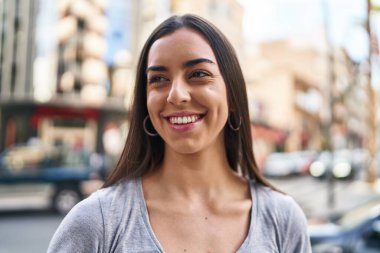 Young beautiful hispanic woman smiling confident looking to the side at street