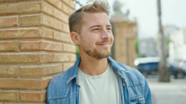 Young caucasian man smiling confident looking to the side at street