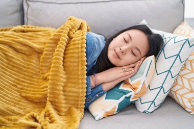 Young chinese woman lying on sofa sleeping at home