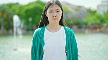 Parkta yüzünde ciddi bir ifade olan genç Çinli kadın.