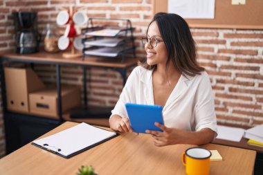 Young hispanic woman business worker using touchpad working at office