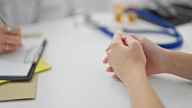 Genç, güzel bir kız doktor ve hasta klinikte sağlık raporu yazıyor.