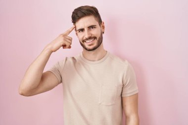 Pembe arka planda duran sakallı İspanyol bir adam tek parmağıyla kafasını işaret ediyor, harika bir fikir ya da düşünce, iyi bir hafıza. 