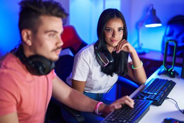 Erkek ve kadın flamalar oyun odasında bilgisayar kullanarak video oyunu oynuyorlar