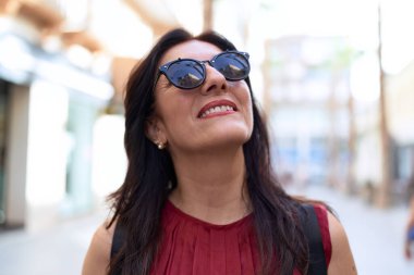 Orta yaşlı İspanyol bir kadın, kendine güvenen bir şekilde caddede gökyüzüne bakıyor.