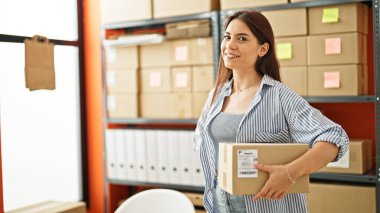 Genç, güzel, İspanyol bir kadın. İş adamı. Ofiste kendine güvenen bir paket tutuyor.