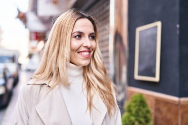Young blonde woman smiling confident looking to the side at street