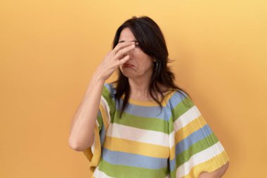 Orta yaşlı İspanyol bir kadın sarı arka planda duruyor. Kokuşmuş ve iğrenç bir koku alıyor. Dayanılmaz bir koku. Kötü kokuyor. 