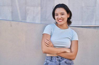 Young hispanic woman standing with arms crossed gesture at street