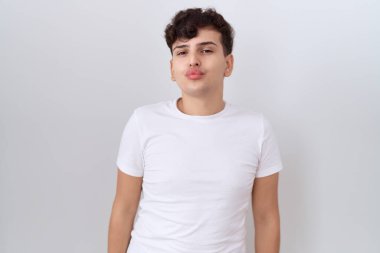 Gündelik beyaz t-shirt giyen genç bir adam kameraya bakıyor ve canlı yayında öpüşüyor. Güzel ve seksi. aşk ifadesi. 