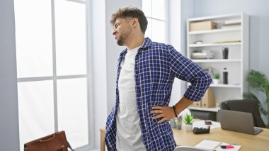 Sessiz sedasız mücadele eden genç Arap adam, iş yerinde çalışırken omurgasına dokunarak şiddetli sırt ağrısı çekiyor.