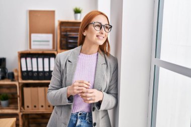 Kafkasyalı genç bir iş kadını ofiste kendinden emin gülümsüyor.