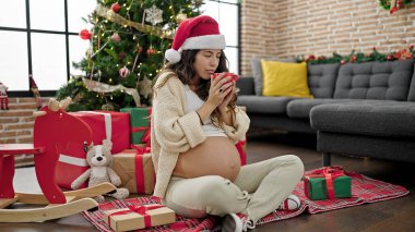 Genç hamile kadın evde Noel 'i kutlamak için kahve içiyor.