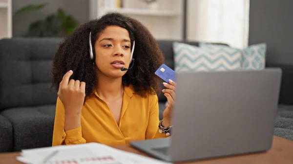 African american woman call center agent having video call holding credit card working at home