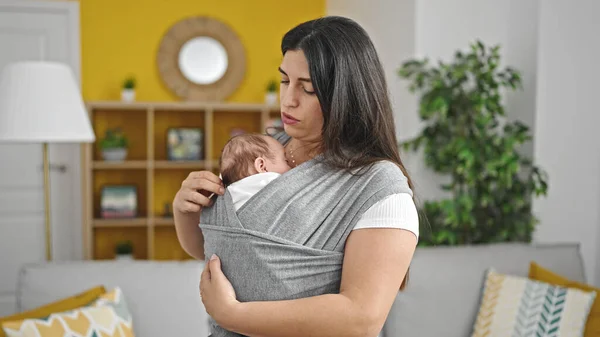 自宅で母性スカーフに赤ちゃんを抱えている母と赤ちゃんの娘 — ストック写真