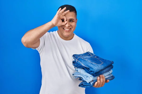 Jeune Homme Hispanique Tenant Pile Jeans Pliés Souriant Heureux Faisant — Photo