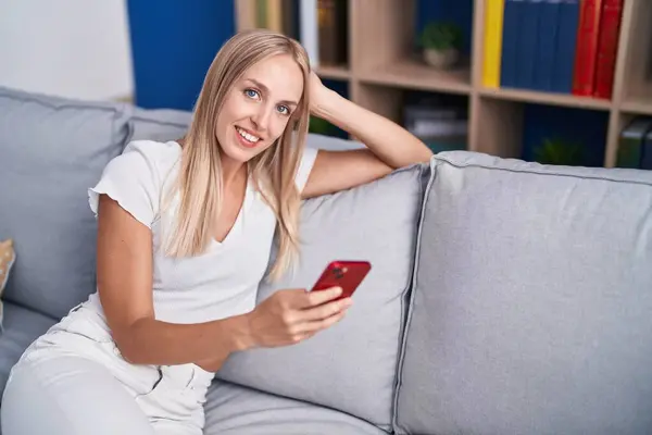 Ung Blondine Kvinde Ved Hjælp Smartphone Sidder Sofaen Derhjemme - Stock-foto