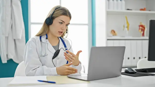 Young blonde woman doctor on video call at clinic