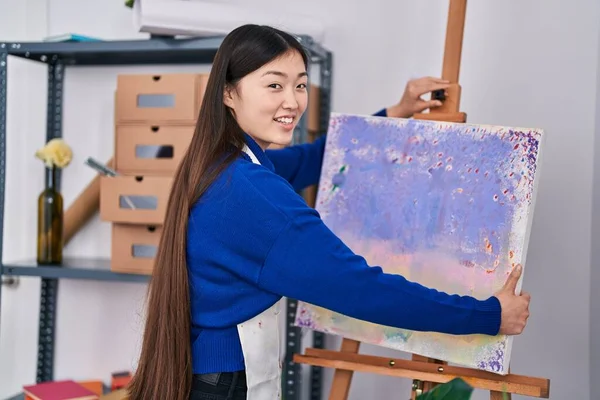 Chinese woman artist smiling confident holding draw at art studio