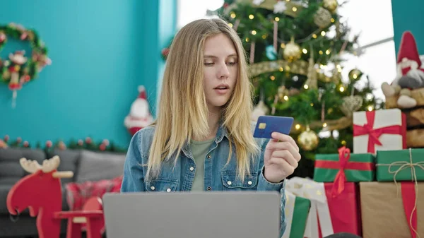 Young blonde woman shopping with laptop and credit card celebrating christmas at home