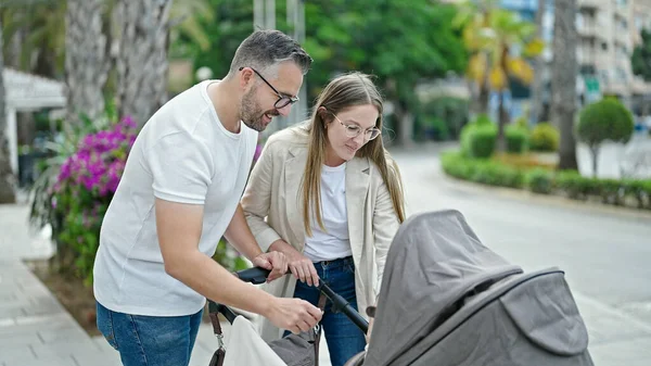 Üç kişilik bir aile sokakta bebek arabasıyla yürüyor.