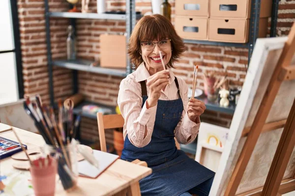 中年女性アーティスト笑顔自信を持って保持絵筆でアートスタジオ — ストック写真