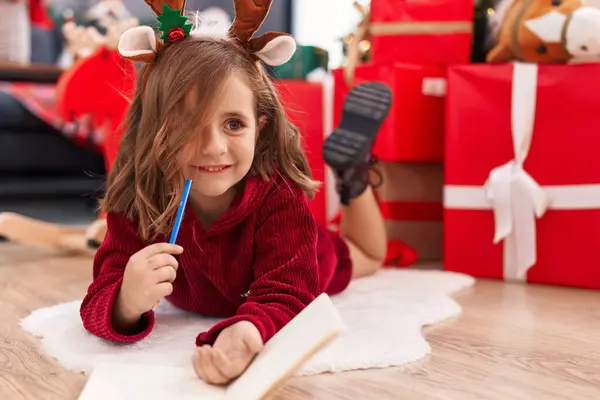 Adorable Hispanic Girl Drawing Notebook Lying Sofa Christmas Tree Home — Zdjęcie stockowe