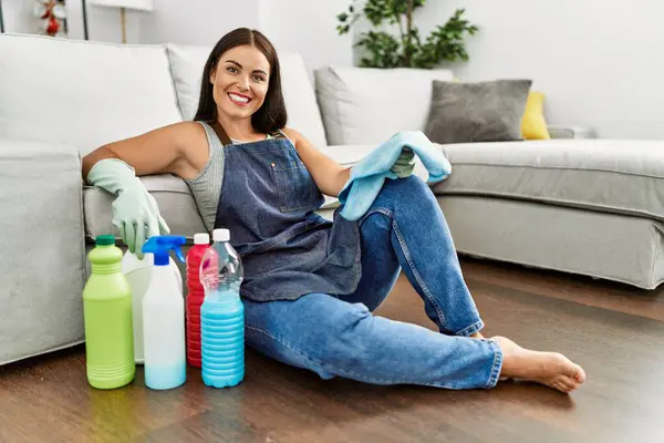 年轻美丽的惊慌失措的女人充满自信地坐在地板上 家里有干净的产品 — 图库照片