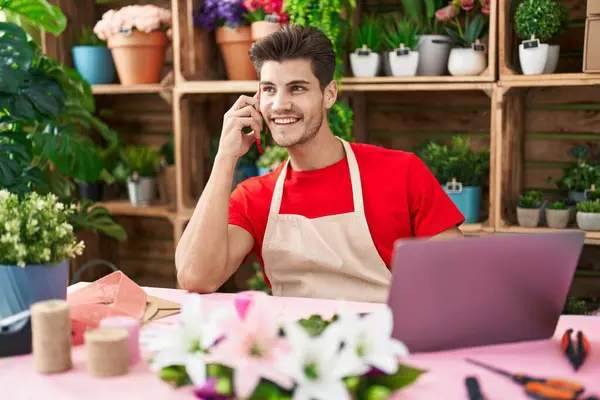 Çiçekçide dizüstü bilgisayar kullanarak konuşan İspanyol çiçekçi.