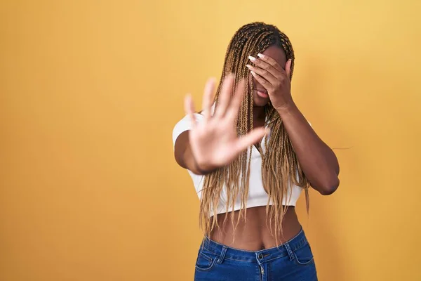 Afroamerykanka Plecionymi Włosami Stojąca Nad Żółtym Tłem Przykrywająca Dłońmi Oczy — Zdjęcie stockowe