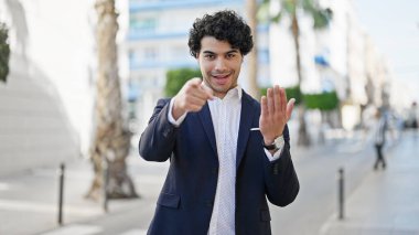 Genç Latin iş adamı güler yüzlü, kendine güler yüzlü, sokak jestleri yapar.